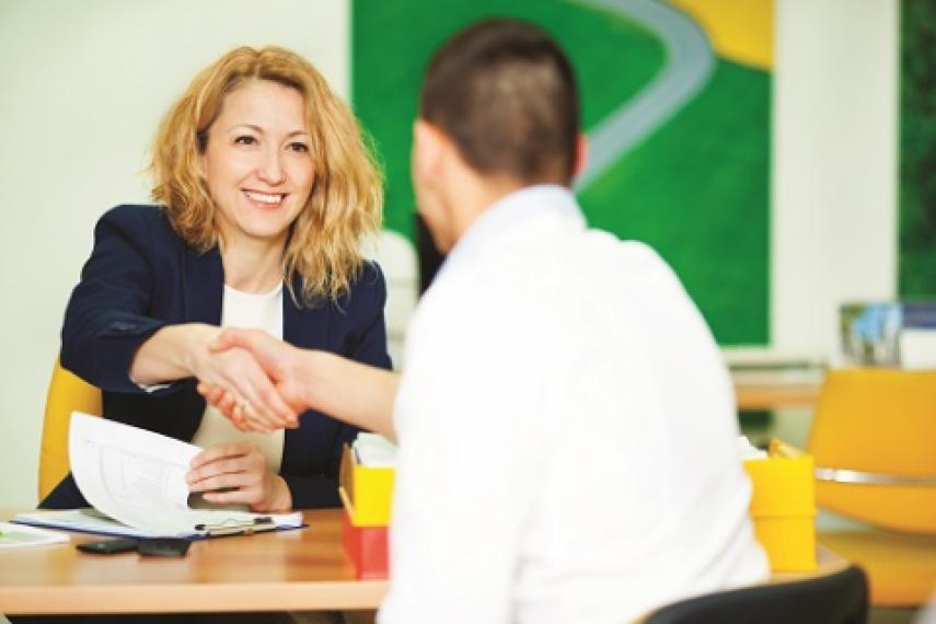 Banker shaking hands across desk with customer