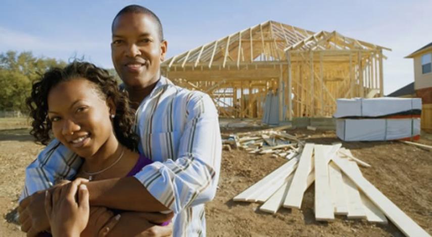 couple embracing in front of house being built